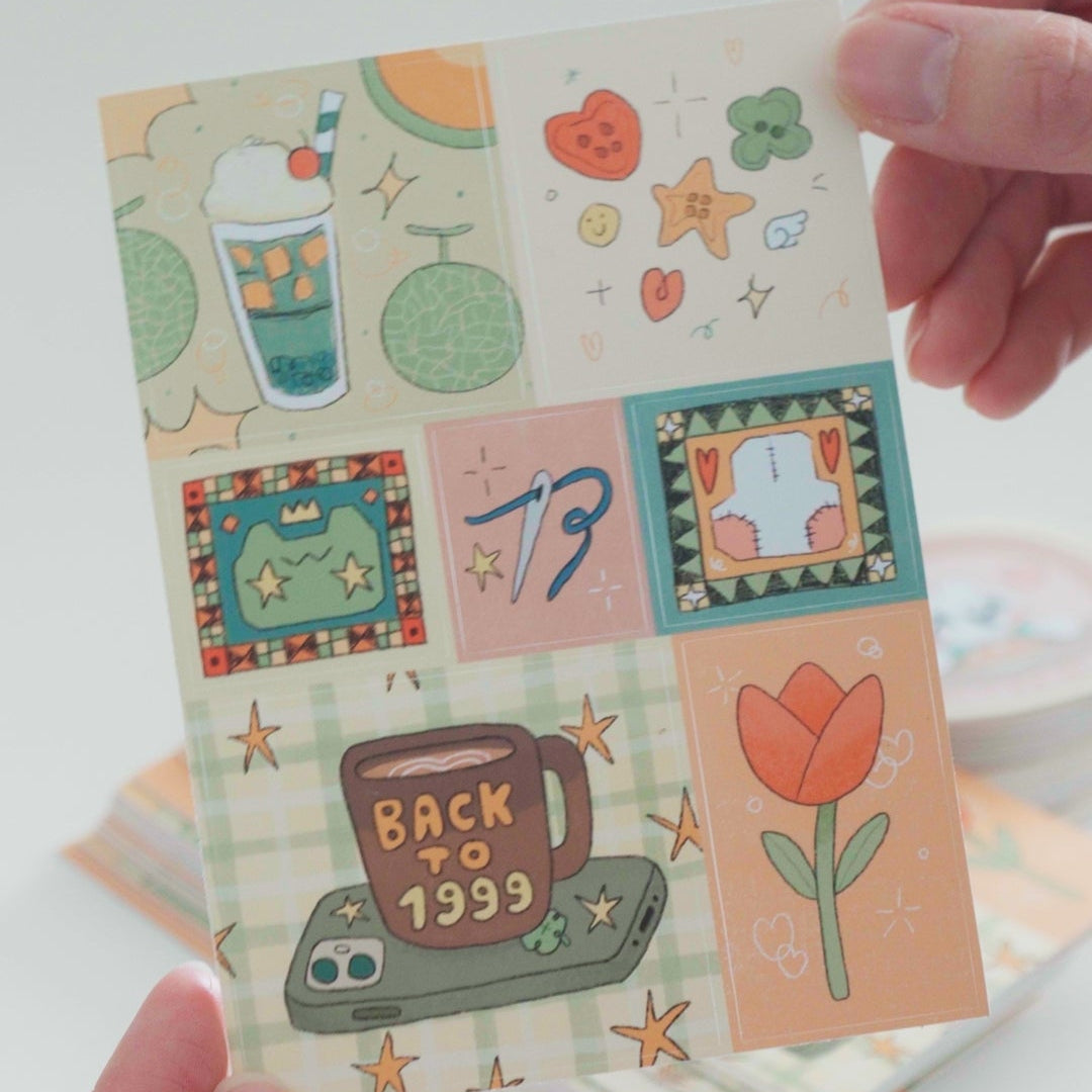 Hand holding a small card with colorful illustrations on a white background